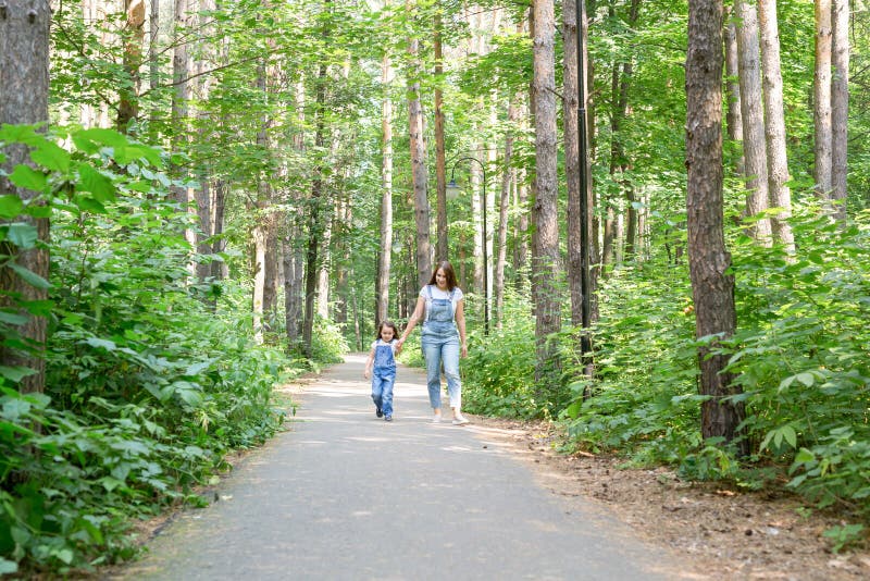 Família, lazer e conceito da natureza - retrato da mãe com sua filha pequena que anda no parque verde no verão imagem de stock Família, lazer e conceito da natureza - retrato da mãe com sua filha pequena que anda no parque verde no verão imagem de stock