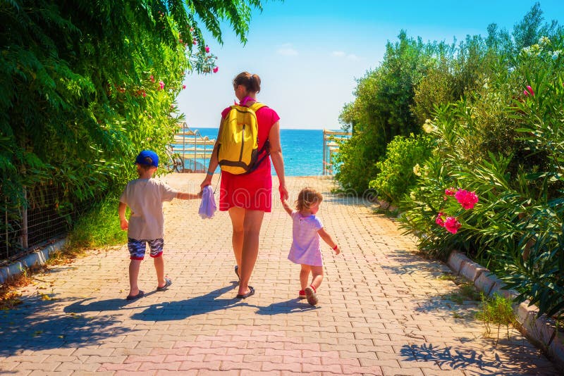A família na mãe do resto do verão e as crianças vão à praia do mar imagem de stock A família na mãe do resto do verão e as crianças vão à praia do mar imagem de stock