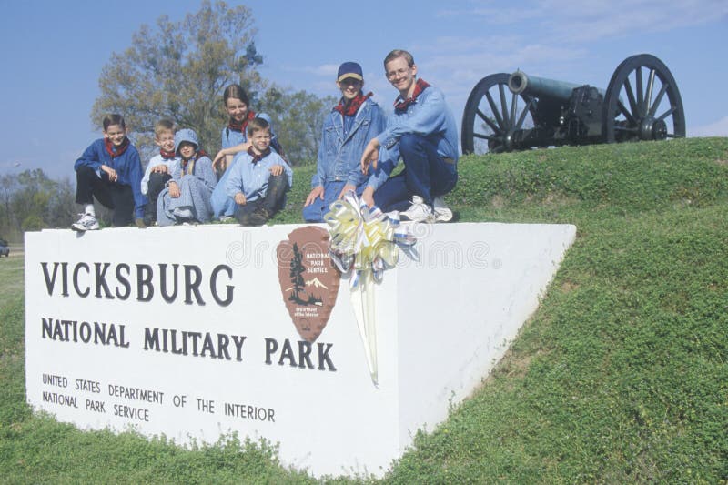 Família no sinal na grama verde na entrada do parque militar nacional de Vicksburg, MS fotografia de stock Família no sinal na grama verde na entrada do parque militar nacional de Vicksburg, MS fotografia de stock