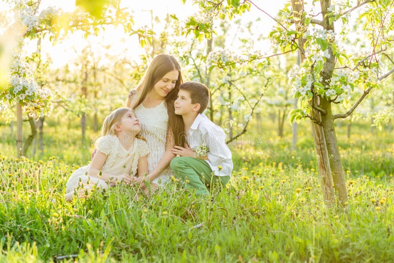 Família nova bonita em um jardim de florescência da mola imagens de stock Família nova bonita em um jardim de florescência da mola imagens de stock