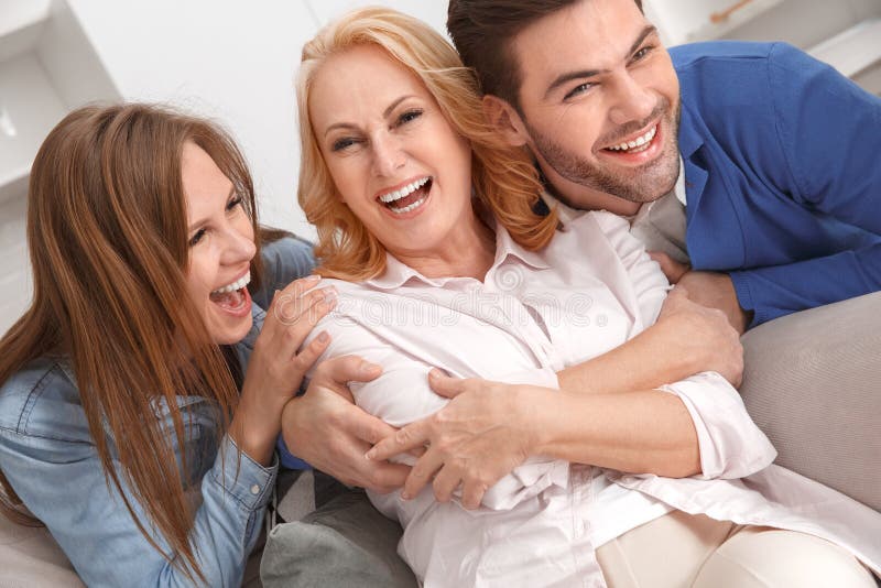 Família nova com o riso do fim de semana da sogra em casa alegre imagem de stock Família nova com o riso do fim de semana da sogra em casa alegre imagem de stock