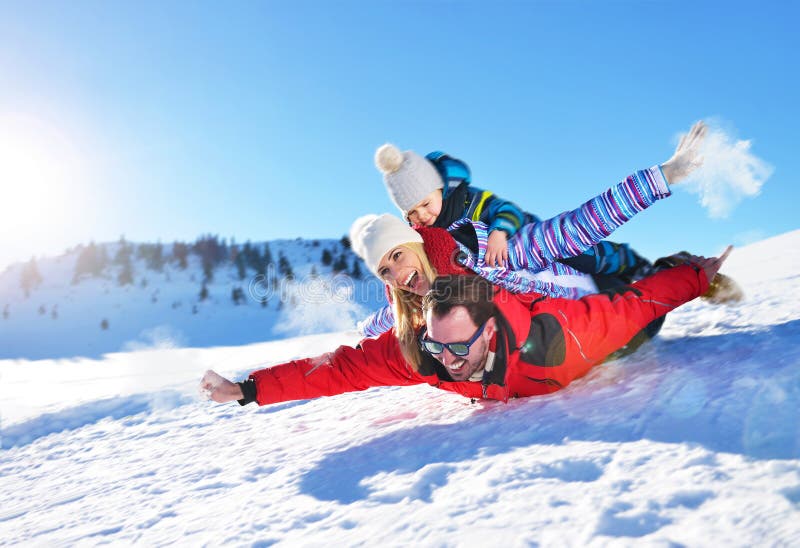 Família nova feliz que joga na neve fresca no dia de inverno ensolarado bonito exterior na natureza fotos de stock Família nova feliz que joga na neve fresca no dia de inverno ensolarado bonito exterior na natureza fotos de stock