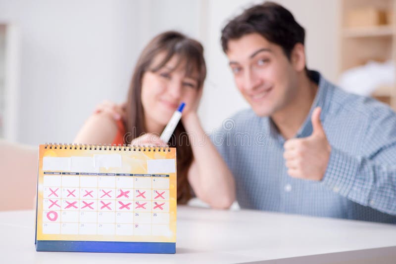 Young family in pregnancy planning concept with ovulation calendar. Young family in pregnancy planning concept with ovulation calendar