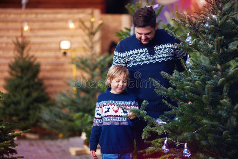 Família, pai feliz e filho comprando uma árvore de Natal por feriados de inverno no mercado sazonal fotografia de stock Família, pai feliz e filho comprando uma árvore de Natal por feriados de inverno no mercado sazonal fotografia de stock