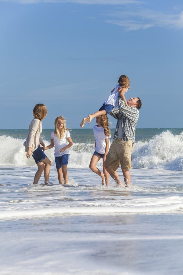 A família Parents as crianças da menina que jogam na praia fotografia de stock A família Parents as crianças da menina que jogam na praia fotografia de stock