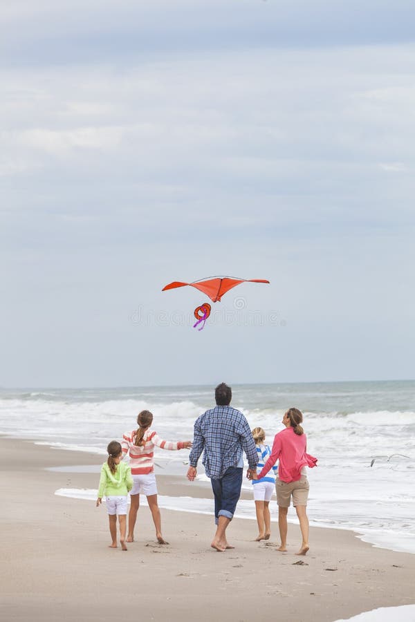 A família Parents as crianças da menina que voam o papagaio na praia fotografia de stock A família Parents as crianças da menina que voam o papagaio na praia fotografia de stock