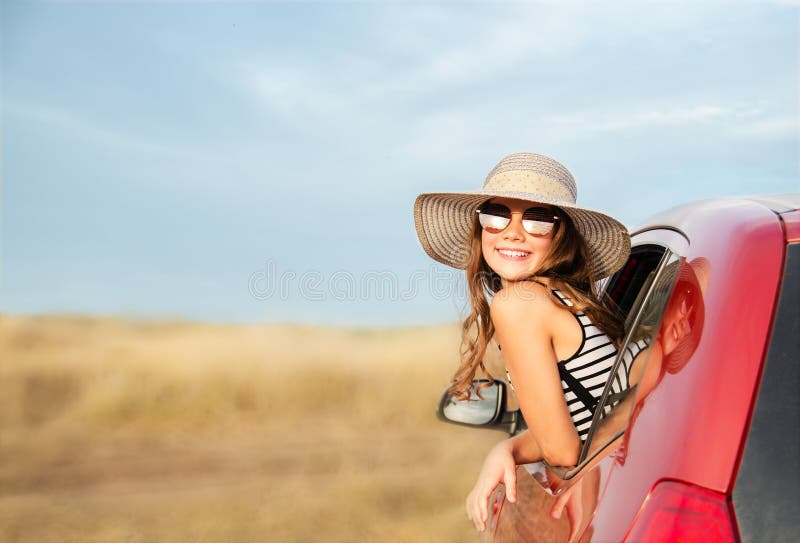 Family ready for the travel on summer vacation. Cute happy smiling little girl child is sitting in the red car with luggage and bags outdoors. Travel trip concept. Family ready for the travel on summer vacation. Cute happy smiling little girl child is sitting in the red car with luggage and bags outdoors. Travel trip concept