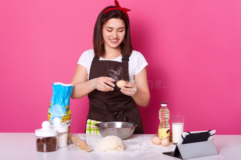 A família que faz panquecas, mulher bonita nova adiciona ovos na massa, preparando-se para a Páscoa, cozendo a pastelaria casei fotos de stock A família que faz panquecas, mulher bonita nova adiciona ovos na massa, preparando-se para a Páscoa, cozendo a pastelaria casei fotos de stock