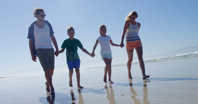 Família que guarda as mãos ao andar na costa na praia