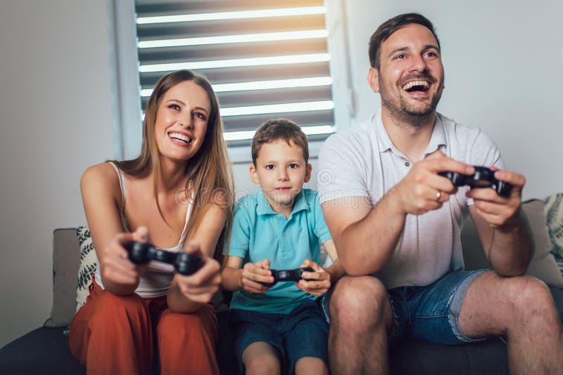 Família que joga jogos de vídeo em casa e que tem o divertimento junto fotos de stock royalty free Família que joga jogos de vídeo em casa e que tem o divertimento junto fotos de stock royalty free