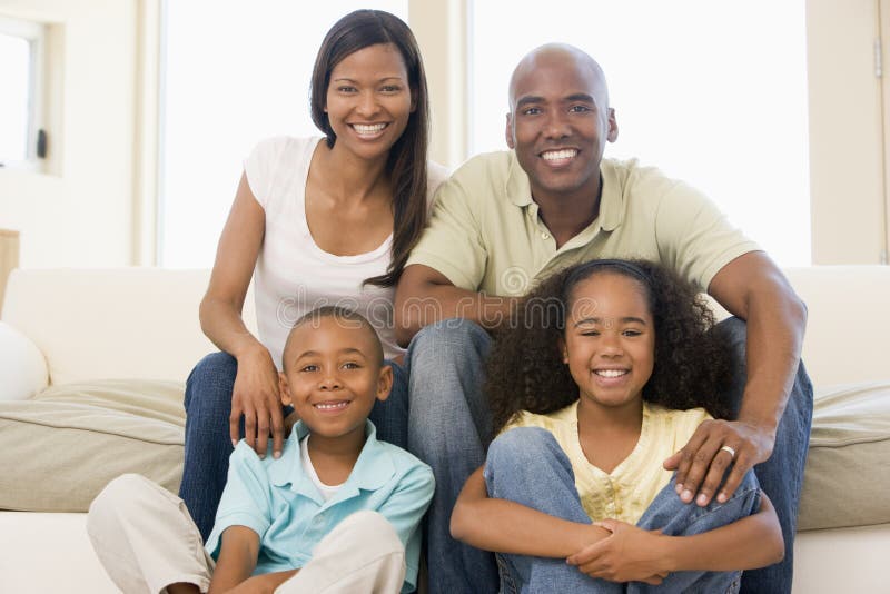 Família que senta-se no sorriso da sala de visitas fotografia de stock Família que senta-se no sorriso da sala de visitas fotografia de stock