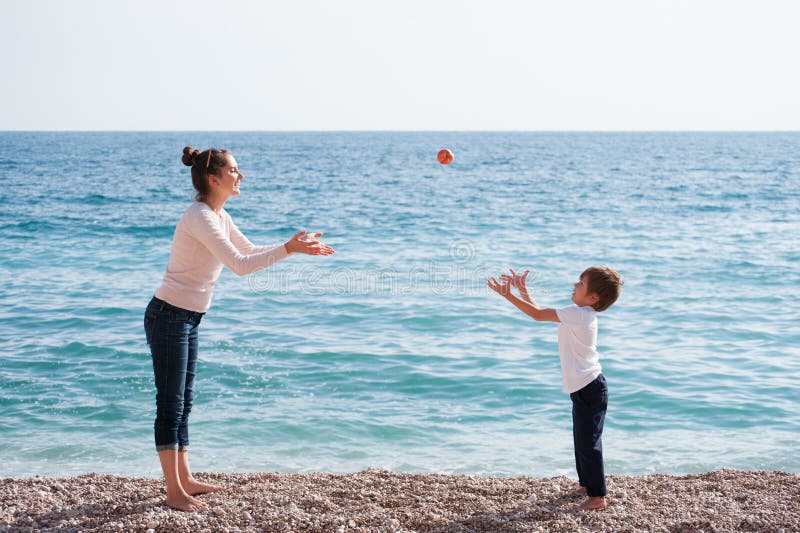 Família saudável feliz que consiste na mãe e na criança que jogam a praia droping da maçã fotos de stock Família saudável feliz que consiste na mãe e na criança que jogam a praia droping da maçã fotos de stock