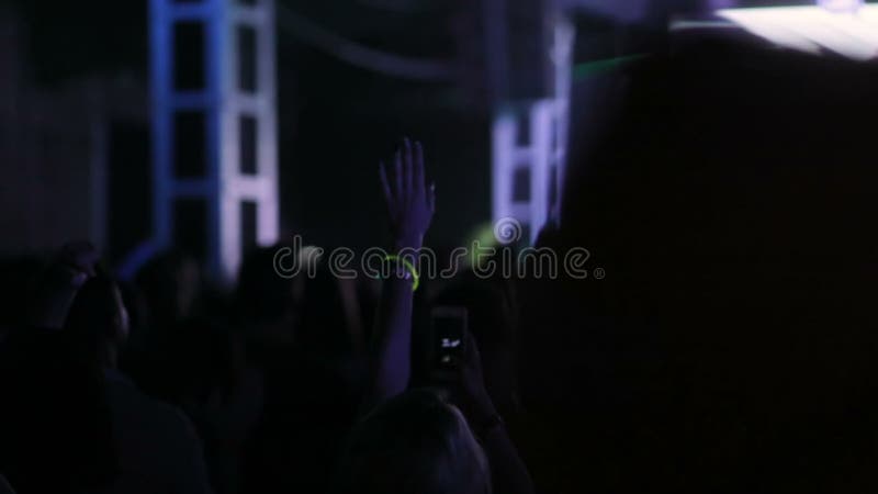 Fan group of people shaking their hands in front of the scene in the concert hall. Energy youth girls boys fashion style