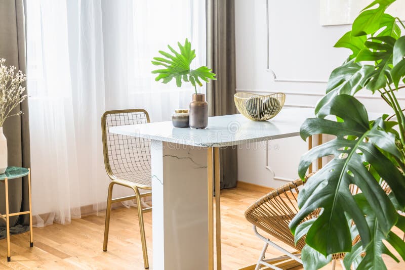 Golden chair at small dining table in chic living room