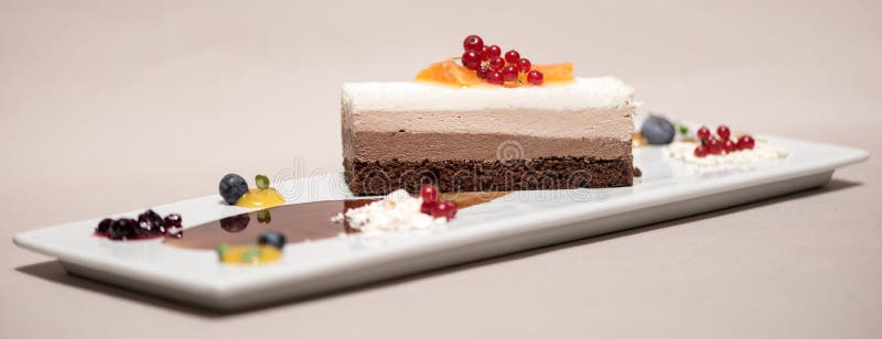 Fancy triple mousse chocolate dessert, decorated with forest fruits and chocolate sauce royalty free stock photography Fancy triple mousse chocolate dessert, decorated with forest fruits and chocolate sauce royalty free stock photography