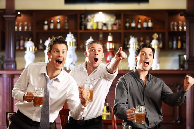 Tre uomini con la birra gioire della vittoria della loro squadra preferita in un pub.