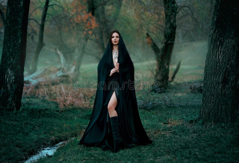 Fantasia misteriosa mulher gótica bruxa escura obcecada pelo mal. vampiro de demônio de menina no capuz de vestido preto. caminhar fotografia de stock royalty free