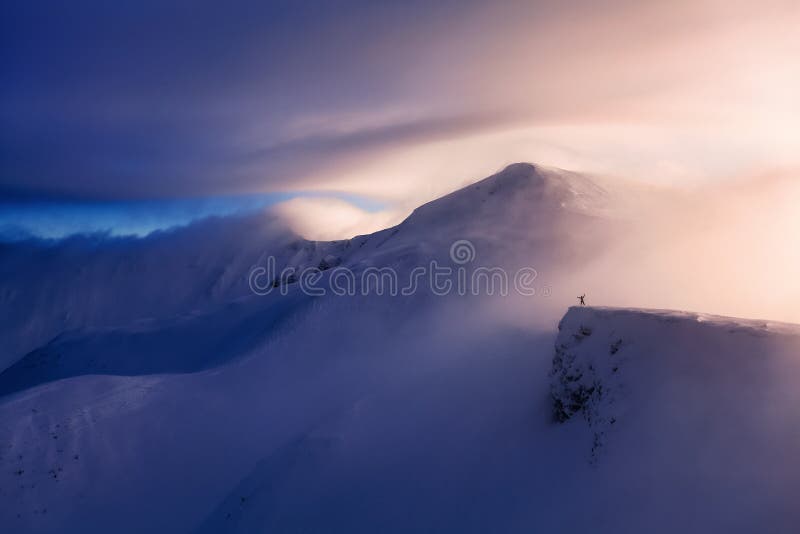 Fantastic scenery with a free rider and mountaineer, high mountains in snow and the fog with interesting colour.