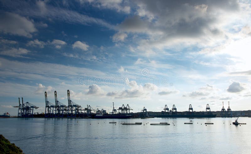 Fantastisk dramatisk himmel, molnbildande och industriellt lastområde på mörk bakgrund. Lastport i Birzebugga, Malta. arkivbild