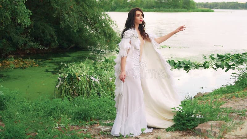 Fantasy kobieta seksowna królowa w długiej białej sukience modelka pozowanie jeziora. kreacyjna peleryna odzieżowa z