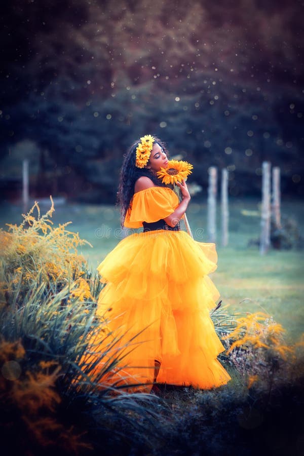 Fantasy magic fairy nymph red hair witch, orange dress beauty lady in the garden with sunflowers. Fantasy magic fairy nymph red hair witch, orange dress beauty lady in the garden with sunflowers