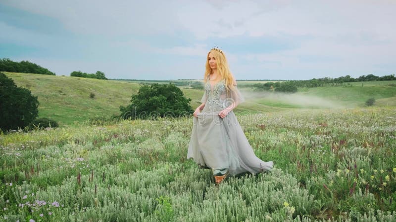 Fantasy szczęśliwa kobieta blondynka księżniczka chodzi w kwitnącej zielonej dolinie łąki zbiory