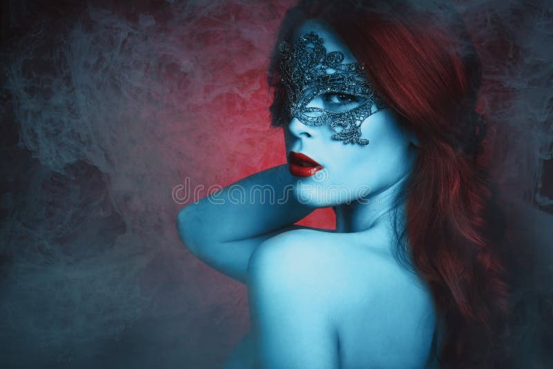 Fantasia di giovane e bella donna con pizzo maschera, la pelle blu e i rossi di capelli in caso di foschia.
