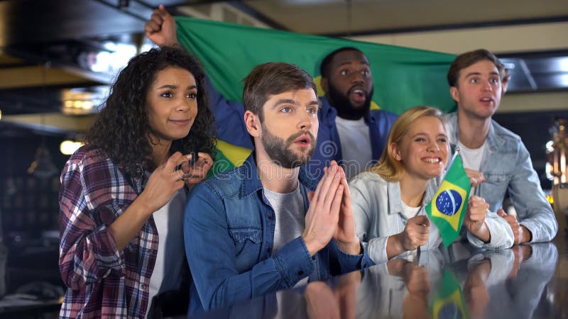 Fanáticos del fútbol ansiosos con las banderas brasileñas que apoyan al equipo nacional en juego foto de archivo libre de regalías Fanáticos del fútbol ansiosos con las banderas brasileñas que apoyan al equipo nacional en juego foto de archivo libre de regalías