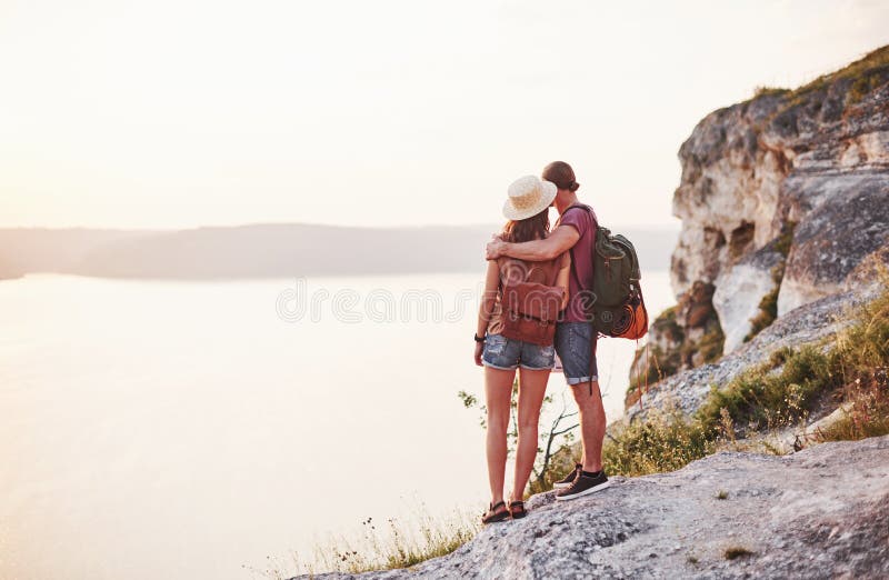 Far away. Young couple have decided to spend their holiday in active way on the edge of the gorgeous rock with lake at