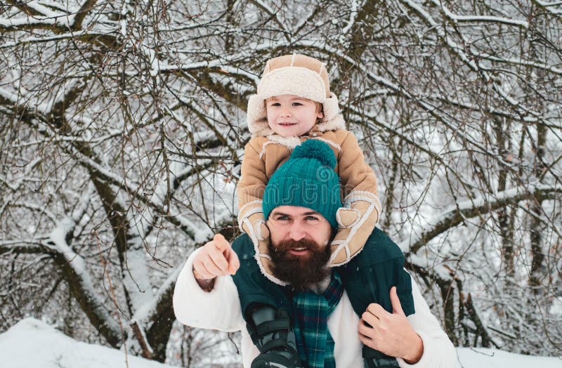 Far som ger son skjuts tillbaka i parken. Söt son kramar sin pappa på vintersemester. Bästa vinterspel för lyckliga familjer fotografering för bildbyråer