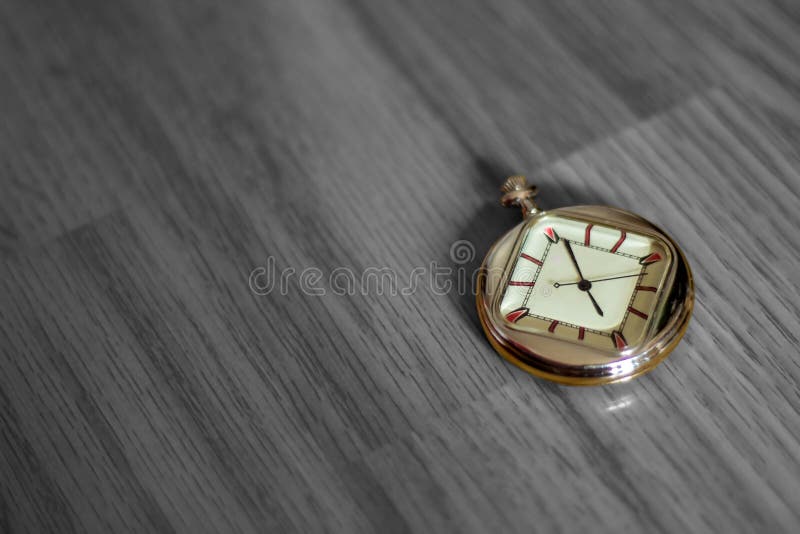Farbige Taschenuhr, die auf einem hölzernen strukturierten Boden in Schwarzweiss liegt stockbild Farbige Taschenuhr, die auf einem hölzernen strukturierten Boden in Schwarzweiss liegt stockbild