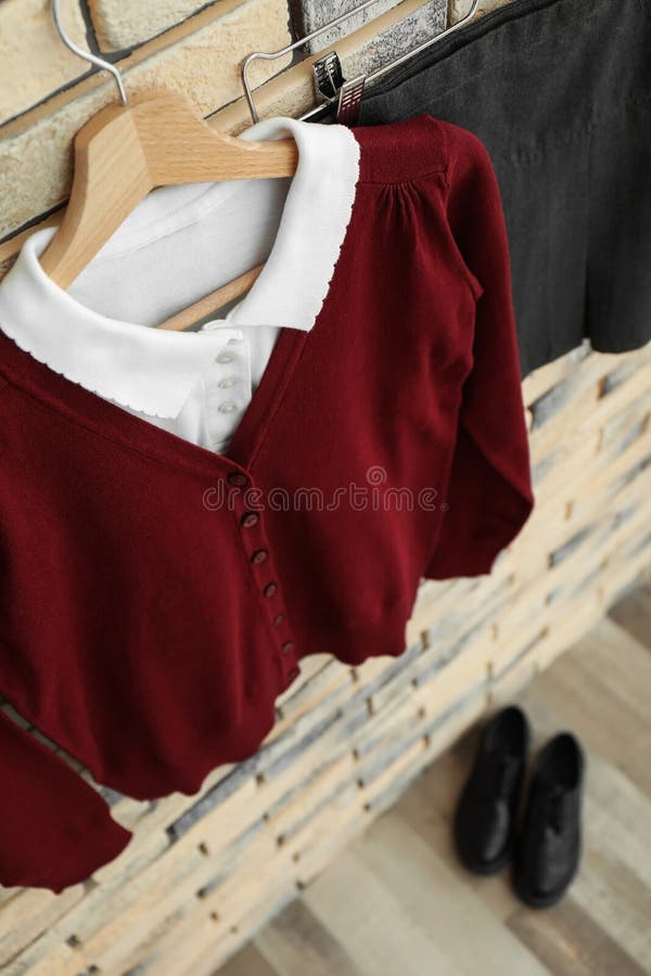 Farda da escola para a menina que pendura na parede de tijolo fotografia de stock royalty free Farda da escola para a menina que pendura na parede de tijolo fotografia de stock royalty free