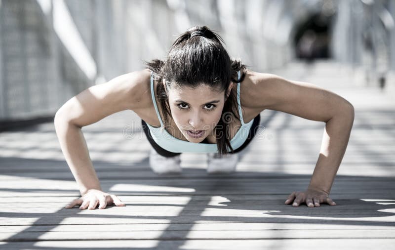 Fare della donna di sport atletico spinge verso l'alto prima di correre nell'allenamento urbano di addestramento