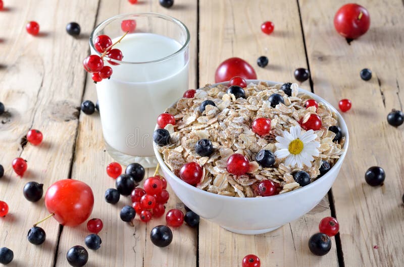 Farina d'avena con le bacche e un vetro di latte fresco su una tavola di legno fotografia stock Farina d'avena con le bacche e un vetro di latte fresco su una tavola di legno fotografia stock