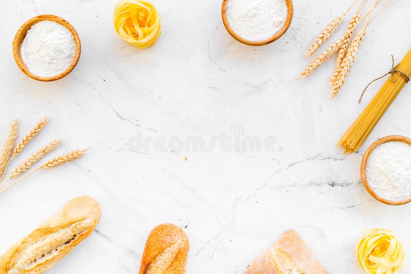 Farinaceous food. Fresh bread and raw pasta near flour in bowl and wheat ears on white stone background top view copy stock photos Farinaceous food. Fresh bread and raw pasta near flour in bowl and wheat ears on white stone background top view copy stock photos