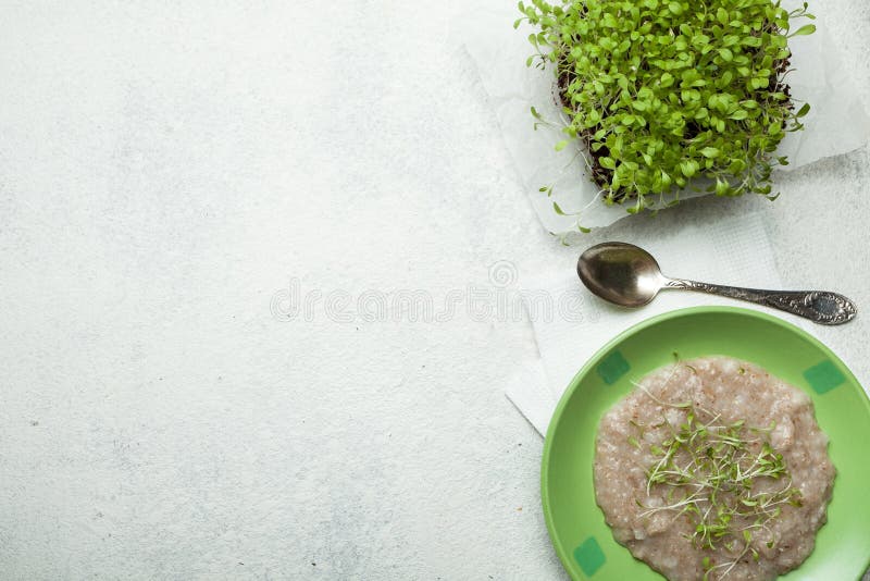 Farinha de aveia em uma bacia verde e em uns micro verdes na mesa de cozinha, vista superior O conceito de reduzir o peso do alim fotografia de stock royalty free Farinha de aveia em uma bacia verde e em uns micro verdes na mesa de cozinha, vista superior O conceito de reduzir o peso do alim fotografia de stock royalty free