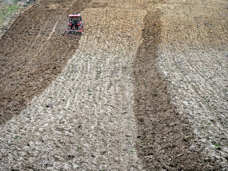 Farm tractor harrowing arable field stock photo