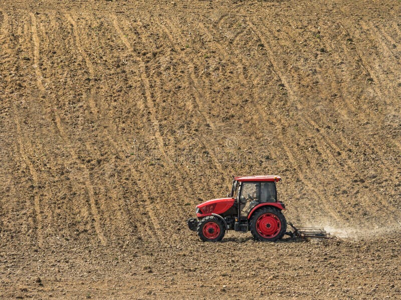 Farm tractor harrowing arable field royalty free stock photo