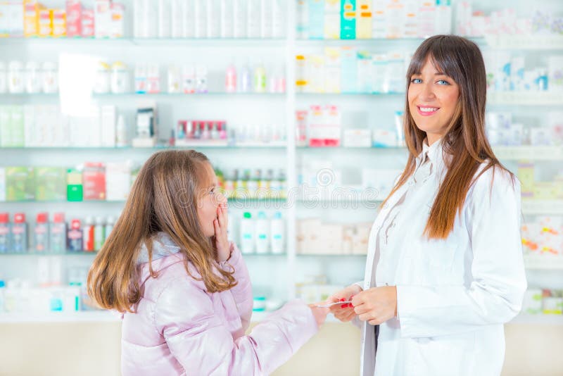 Farmaceuta daje witaminom dziecko dziewczyna w aptece fotografia stock Farmaceuta daje witaminom dziecko dziewczyna w aptece fotografia stock