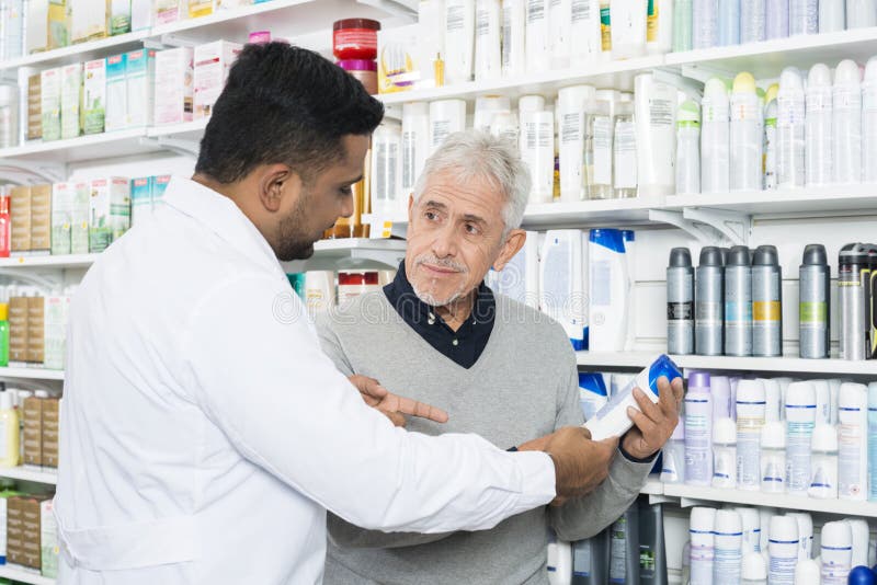 Farmacista Assisting Senior Customer in prodotto d'acquisto fotografie stock libere da diritti Farmacista Assisting Senior Customer in prodotto d'acquisto fotografie stock libere da diritti