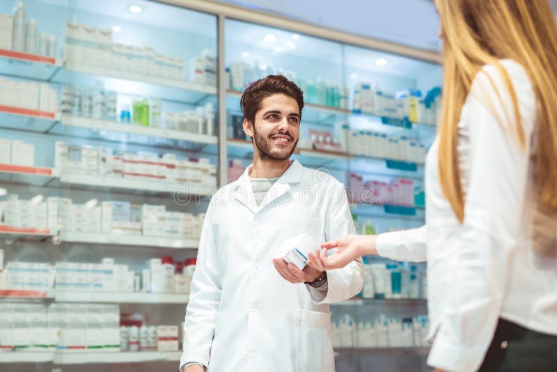 Farmacêutico experiente que aconselha o cliente fêmea na farmácia foto de stock Farmacêutico experiente que aconselha o cliente fêmea na farmácia foto de stock