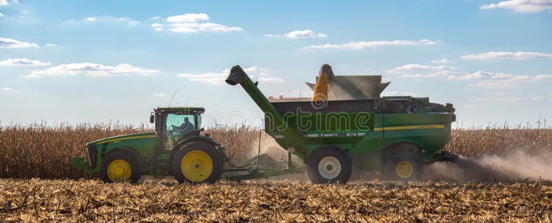 A farmer driving his John Deere tractor pulling a grain hopper stock photos