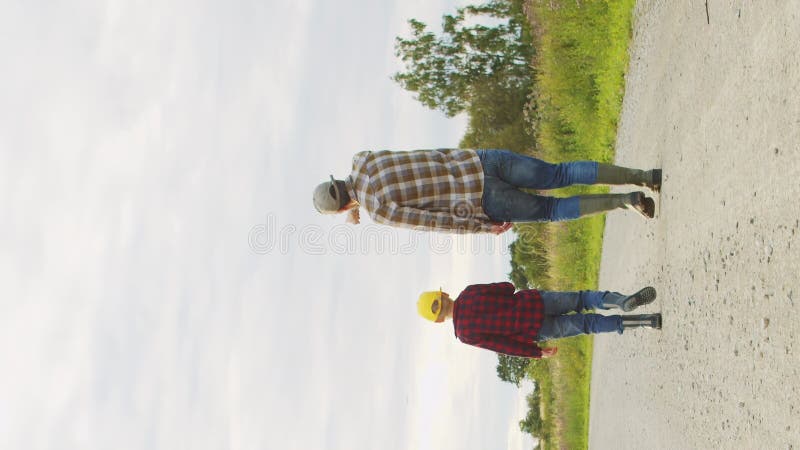 Farmer and his son in front of a sunset agricultural landscape. Man and a boy in a countryside field. Fatherhood stock video