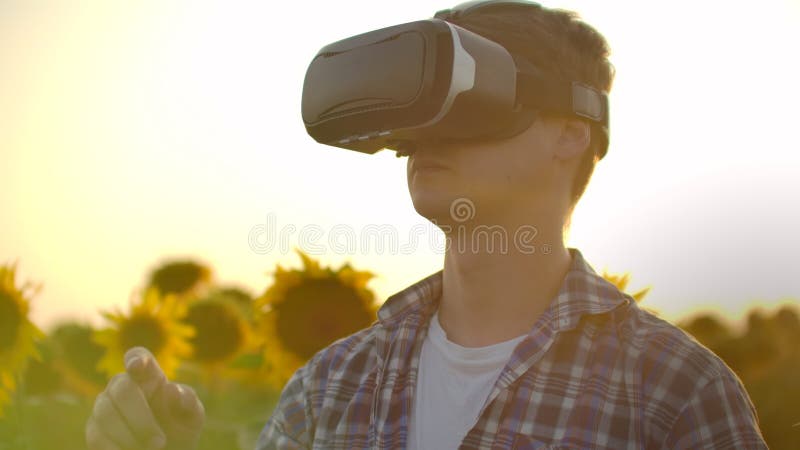 The farmer manager is working in VR glasses at sunset in nature
