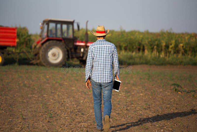 Farmer with tablet in front of tractor