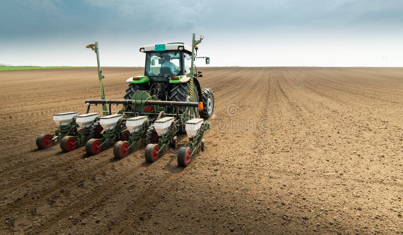Farmer with tractor seeding sowing crops at agricultural field stock photo Farmer with tractor seeding sowing crops at agricultural field stock photo