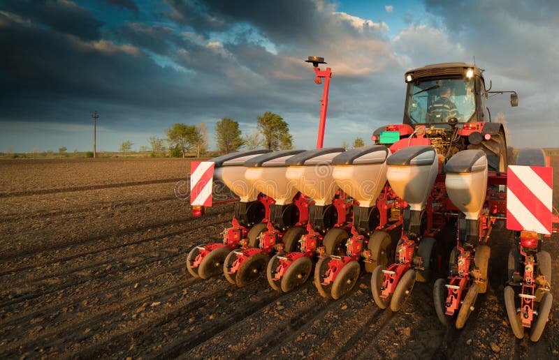 Farmer with tractor seeding - sowing crops at agricultural field