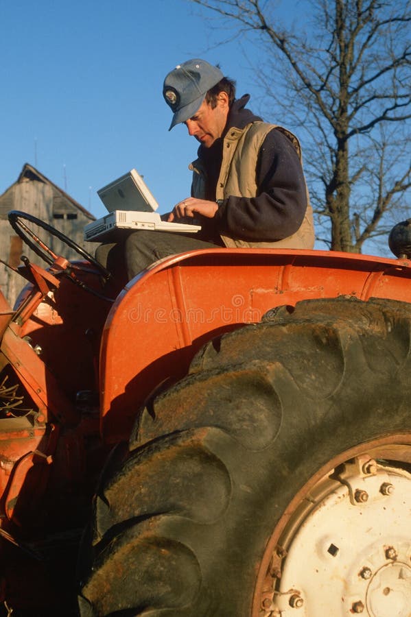 Farmer on tractor working on laptop computer stock image