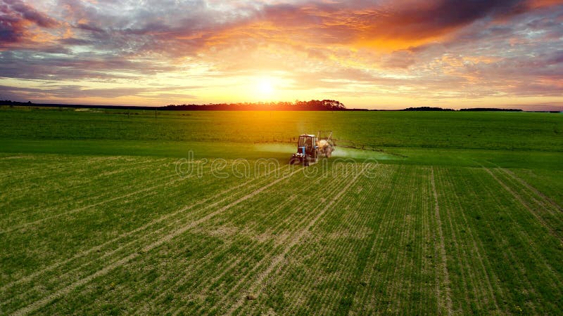 Farmer working in the field on a tractor until sunset stock image