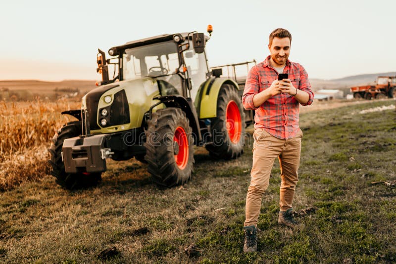 Male Farmer working on field using smartphone in modern agriculture - tractor and trailer background royalty free stock photos Male Farmer working on field using smartphone in modern agriculture - tractor and trailer background royalty free stock photos